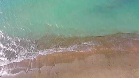 Playa-De-Arena-Y-Agua-Ondulada-Del-Océano-En-Vista-Aérea-De-Arriba-Hacia-Abajo