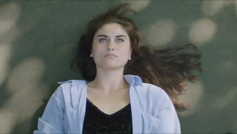 young woman lying down outdoors with dappled light