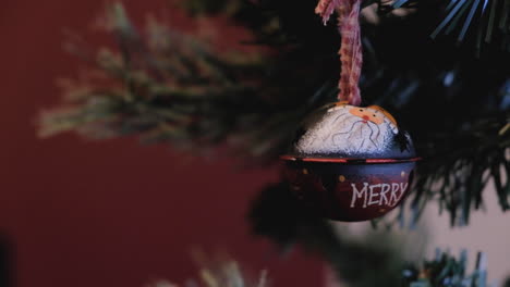 Rojo-Santa-Claus-Con-Feliz-Inscripción-Adorno-Navideño-Colgando-Del-árbol-Disparo-Detallado-Fondo-Rojo-Borroso