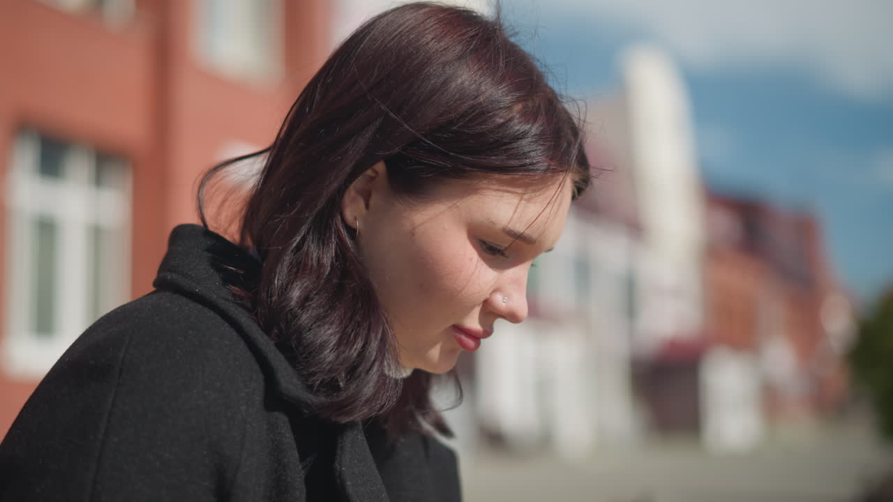 빛으로 조명된 머리카락이 바람에 부드럽게 흔들리고 부드러운 빛이 그녀의 특징을 강조하며, 배경은 부드러운 보케 효과로 흐릿합니다.