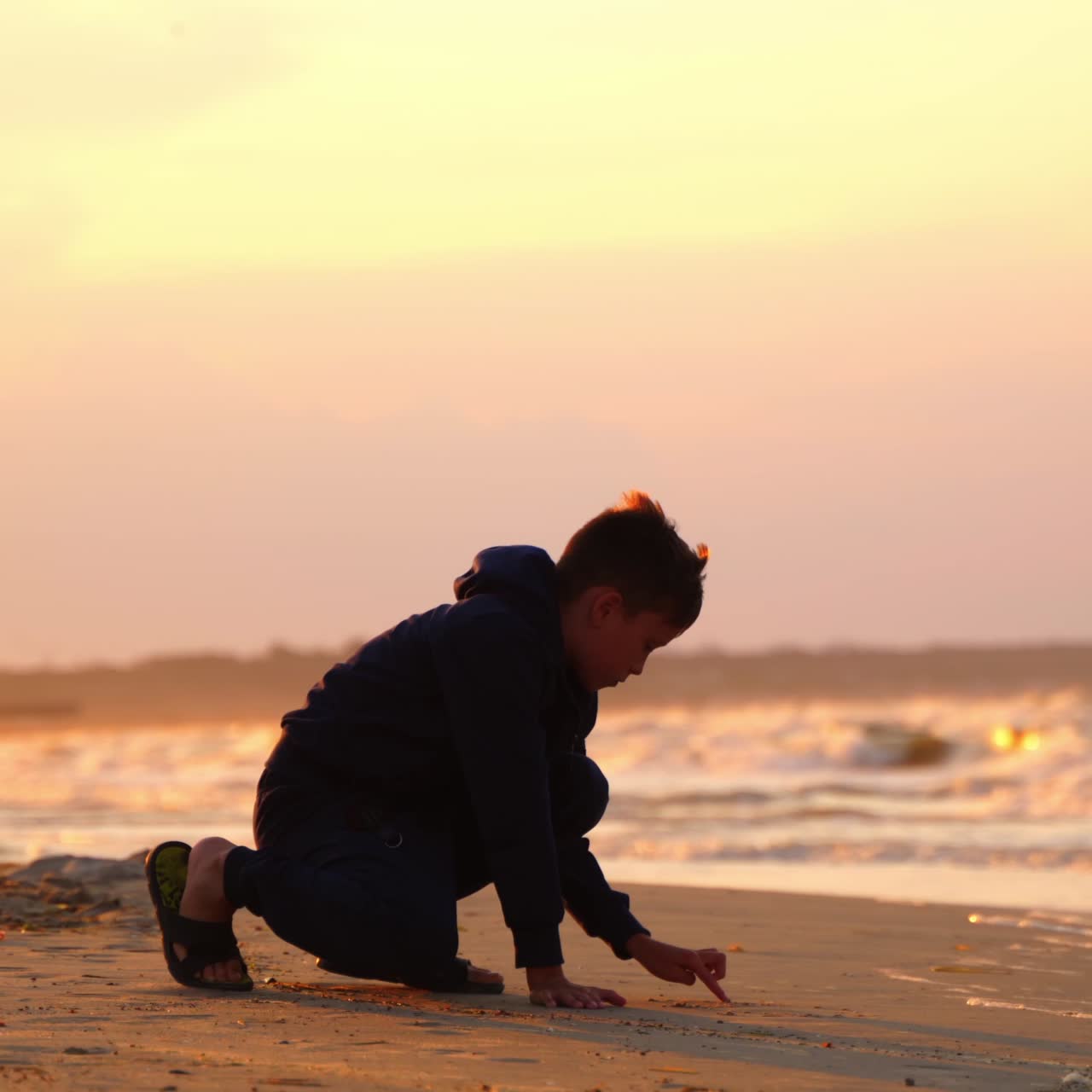 Boy drawing word on sand