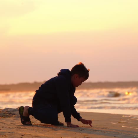 boy drawing word on sand