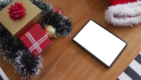 tableta con espacio de copia en la pantalla acostada en la mesa con sombreros de santa y regalos de navidad