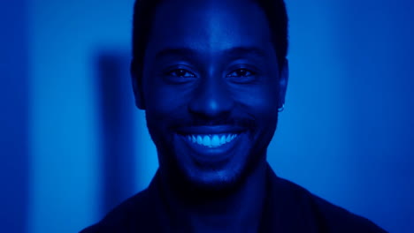 close-up portrait of a smiling man under blue light