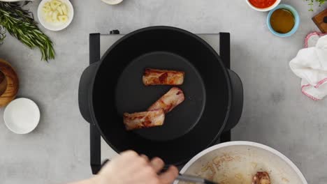 persona del cultivo cocinando costillas en la sartén