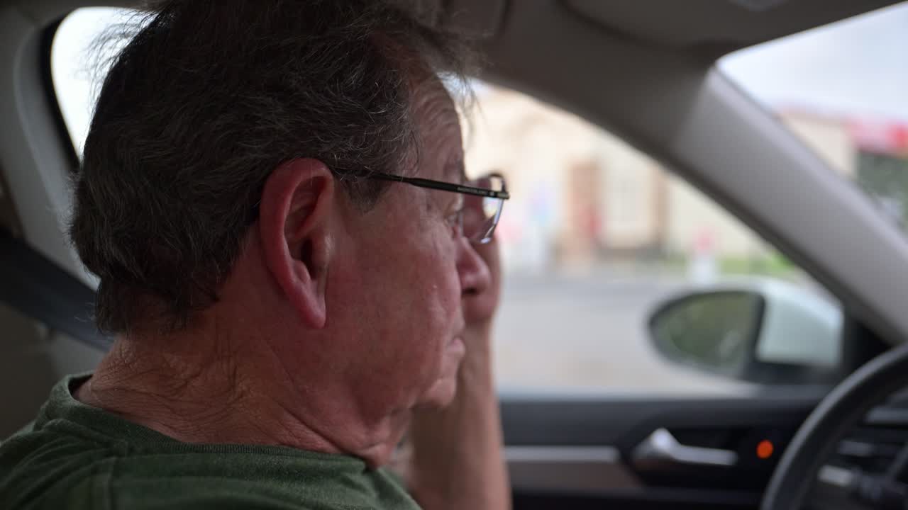 안경을 쓴 노인이 비가 내린 후 운전합니다.