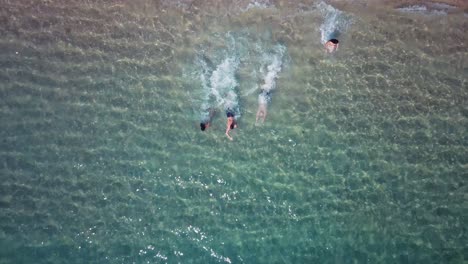 grupo de amigos corre y salta al agua cristalina en la playa