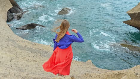 mujer de vestido rojo admira el océano atlántico y la costa volcánica de tenerife