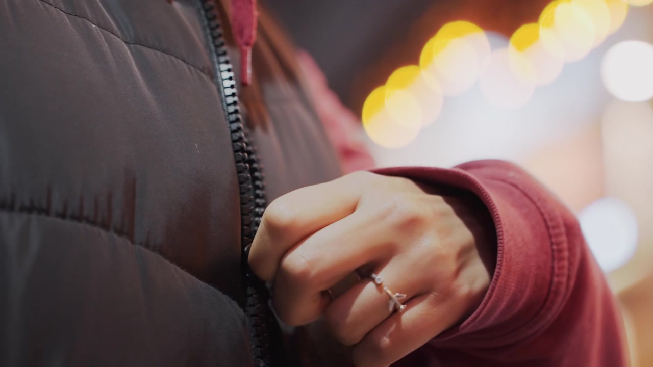 Nighttime urban coat with lights. Detailed view of jacket zipper amid city lights during night. Intimate shot of urban clothing featuring zipper and textured fabric in night city environment