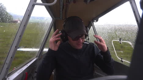 static slow motion fhd shot of a male pilot sitting in the cockpit, putting on his headphone set, adjusting the microphone and preparing to take off