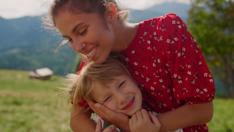 Portrait-smiling-mother-daughter-on-family-vacation-standing-mountains-valley.