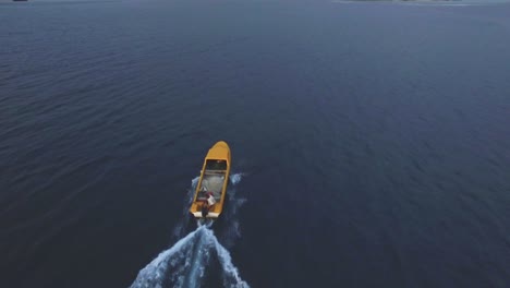 tracking aerial view on small motorboat sailing offcoast in calm water of tropical sea