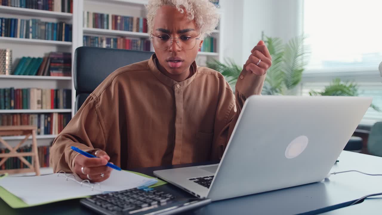 Young african american woman counts on calculator and gets very upset