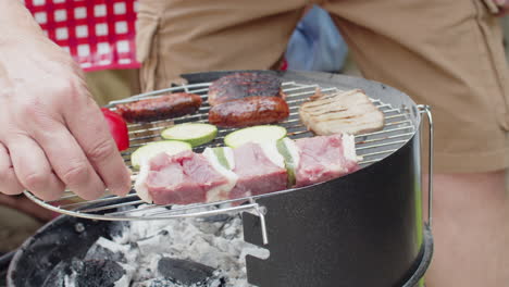 close-up of an unrecognizable man putting kebab on grill