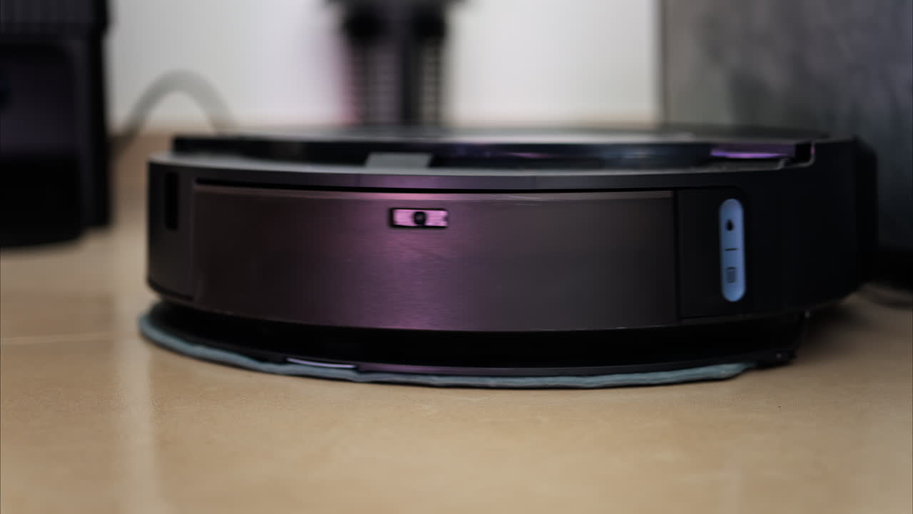 Close up of a black robot vacuum cleaner moving and rotating on the floor tiles