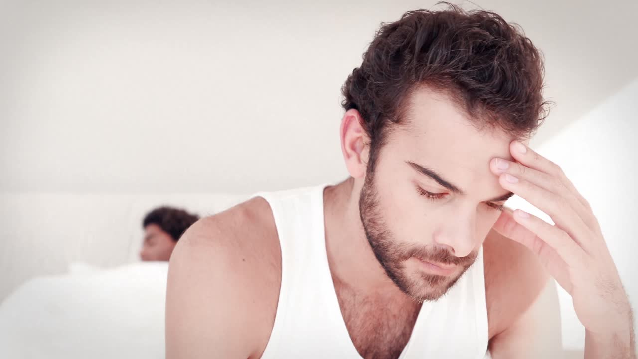 침대에 앉아 있는 두통 을  ⁇ 고 있는 사람