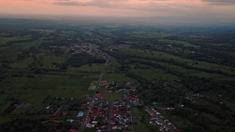 expansive aerial view of la fortuna, costa rica's lush green rural landscape and scattered towns, bathed in the tranquil, golden light of sunset