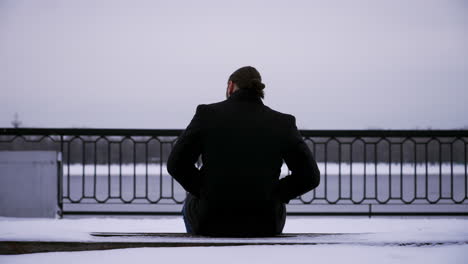 Man-sitting-on-a-bench-with-snow