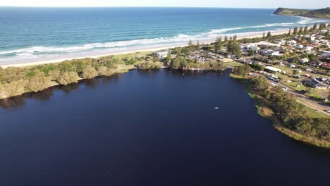 beach with lake ainsworth in lennox head, nsw, australia - aerial pullback