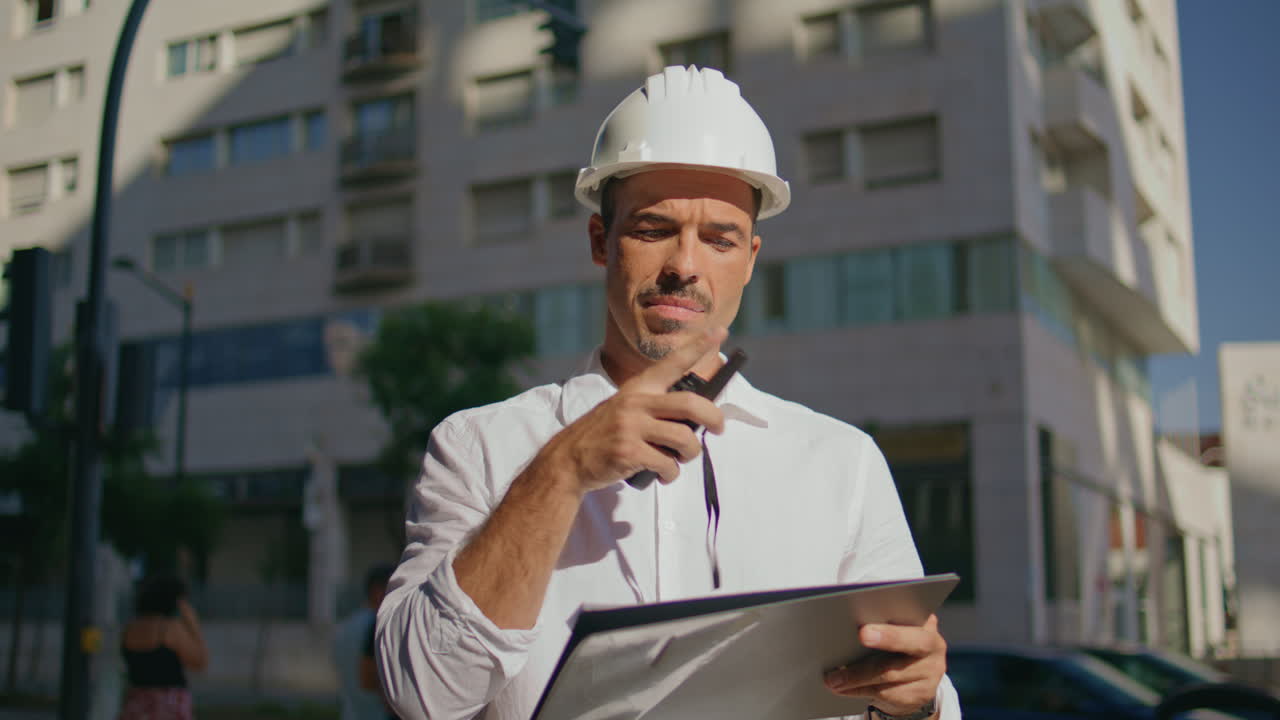 Serious architect dictate instructions using portable radio at street closeup