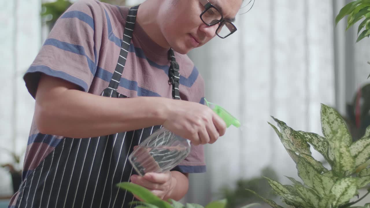 집에서 식물에 물을 주고 있는 아시아인 남자
