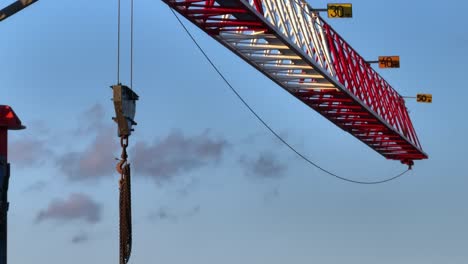 fast-paced aerial video of the structure of a crane, a hook hangs from its arm and chains hang from the arm