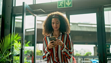 a woman with curly hair using a smartphone indoors