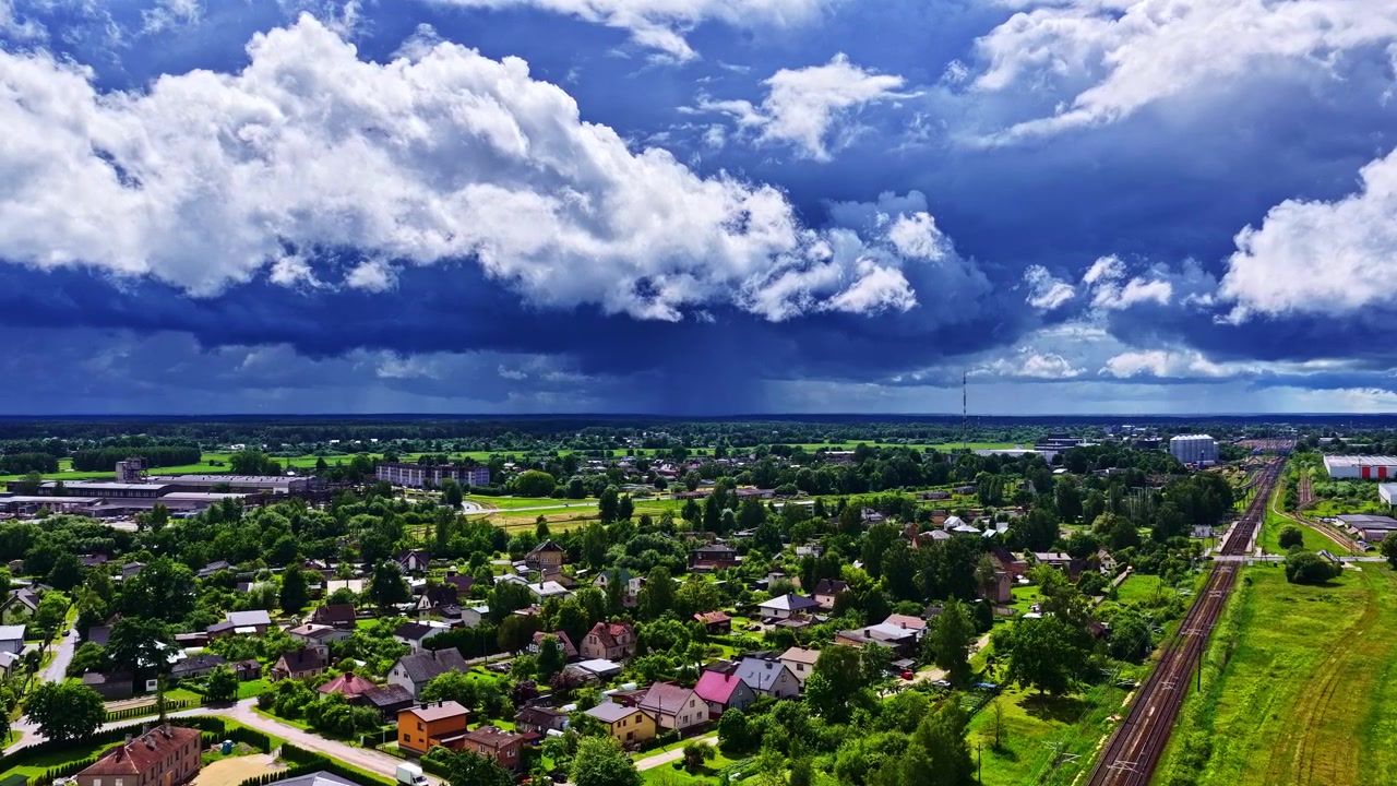 Những đám mây bão đen ấn tượng hình thành trên một thị trấn nhỏ ở châu Âu với cây xanh và đường sắt.
