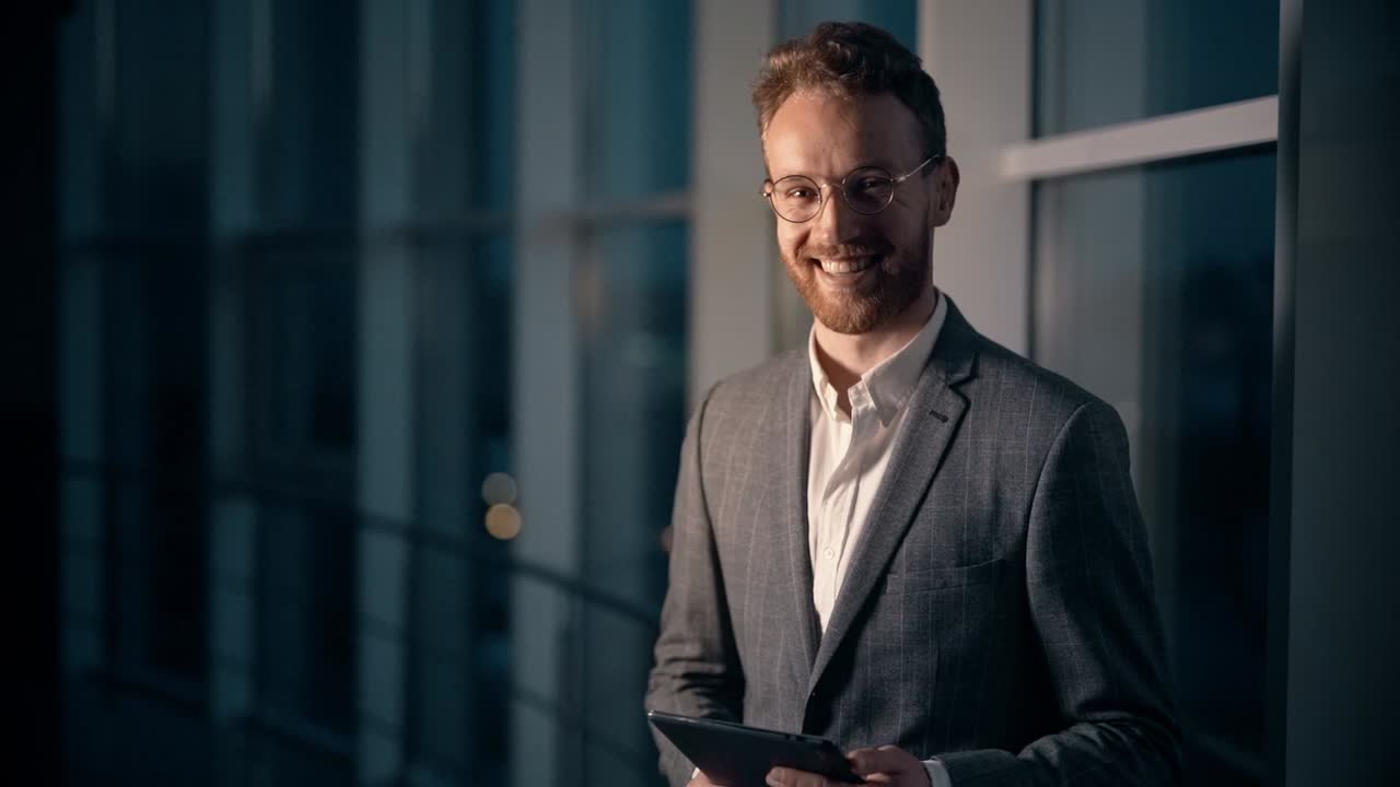 retrato da cintura para cima de um jovem em um terno de negócios sorrindo para a câmera no fundo da cidade à noite
