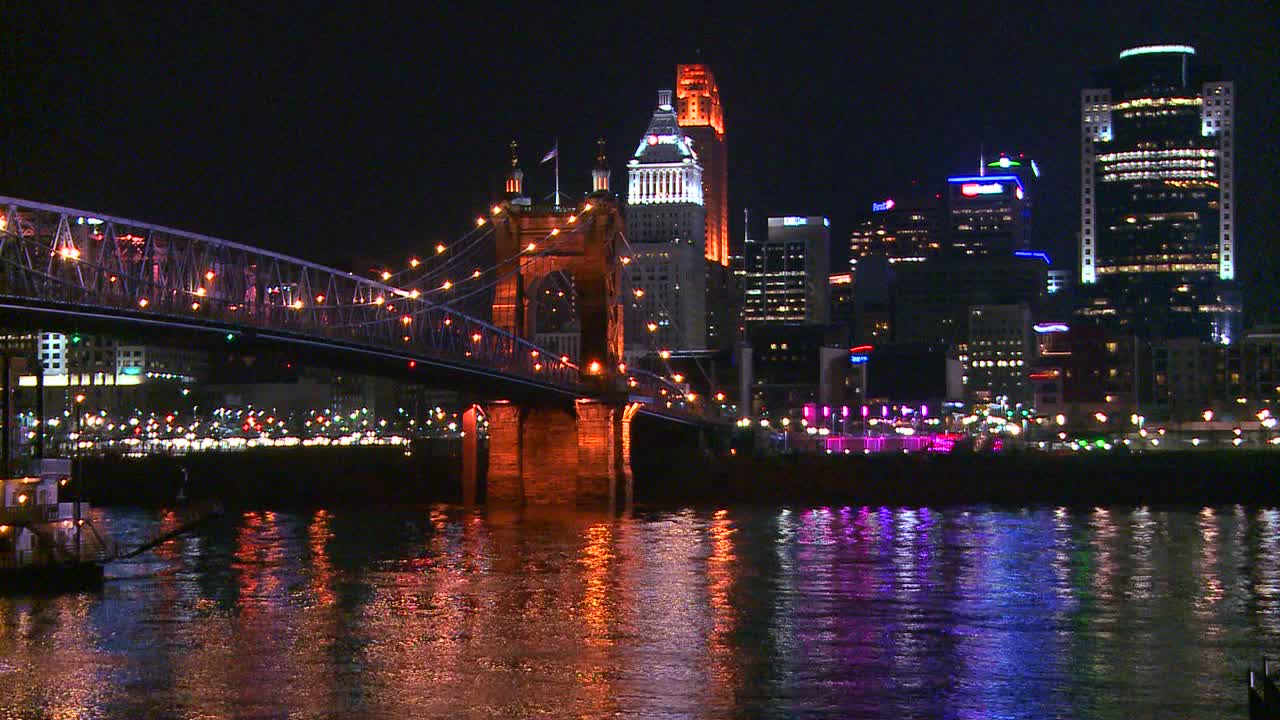 Light reflects off the Ohio River with the city of Cincinnati Ohio background as a riverboat passes underneath