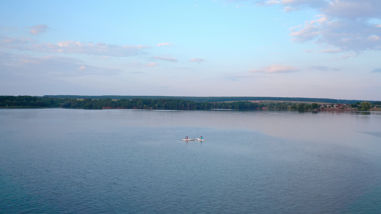 Young people sailing on water. Man and woman traveling on river on paddle boards on industry background in the evening. Summer rest concept