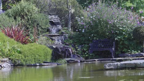 Zeitraffer-Des-Kleinen-Wasserfalls-Und-Einer-Bank-Im-Garten