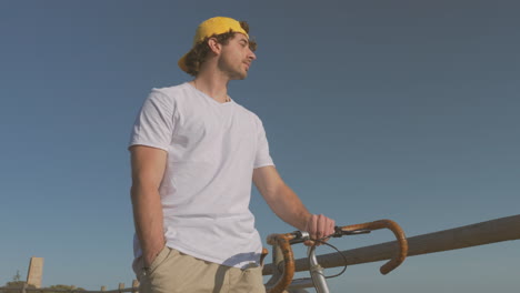 hombre con bicicleta caminando por el paseo marítimo