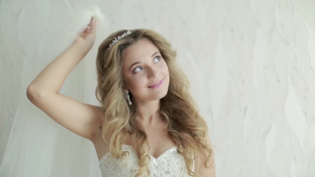 Sposa che tiene il velo. Bellissima giovane sposa con velo in abito nuziale bianco.