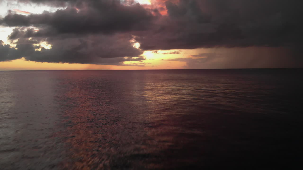 clean ocean view aerial, flying at speed over calm sea colored by a pink orange sunset reflection, Kokomo Beach, Caribbean waters