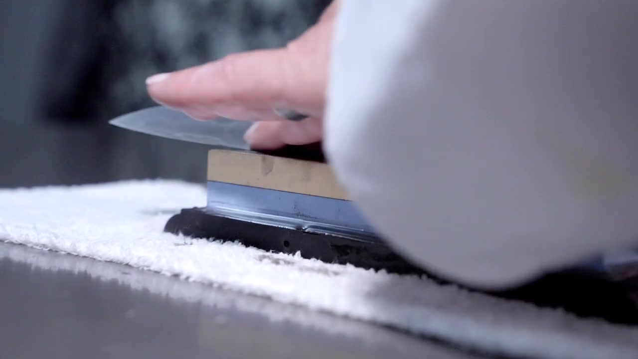 An up-close shot of a chef sharpening his knife with precision. Ideal for culinary content, showcasing essential kitchen skills and tool preparation in high detail.