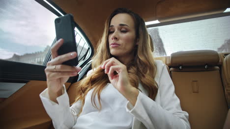 Relaxed-business-lady-talking-on-video-call-on-smartphone-in-modern-car.