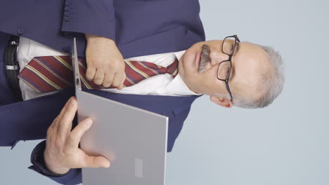 Vertical-video-of-Old-businessman-looking-at-laptop-with-excitement.