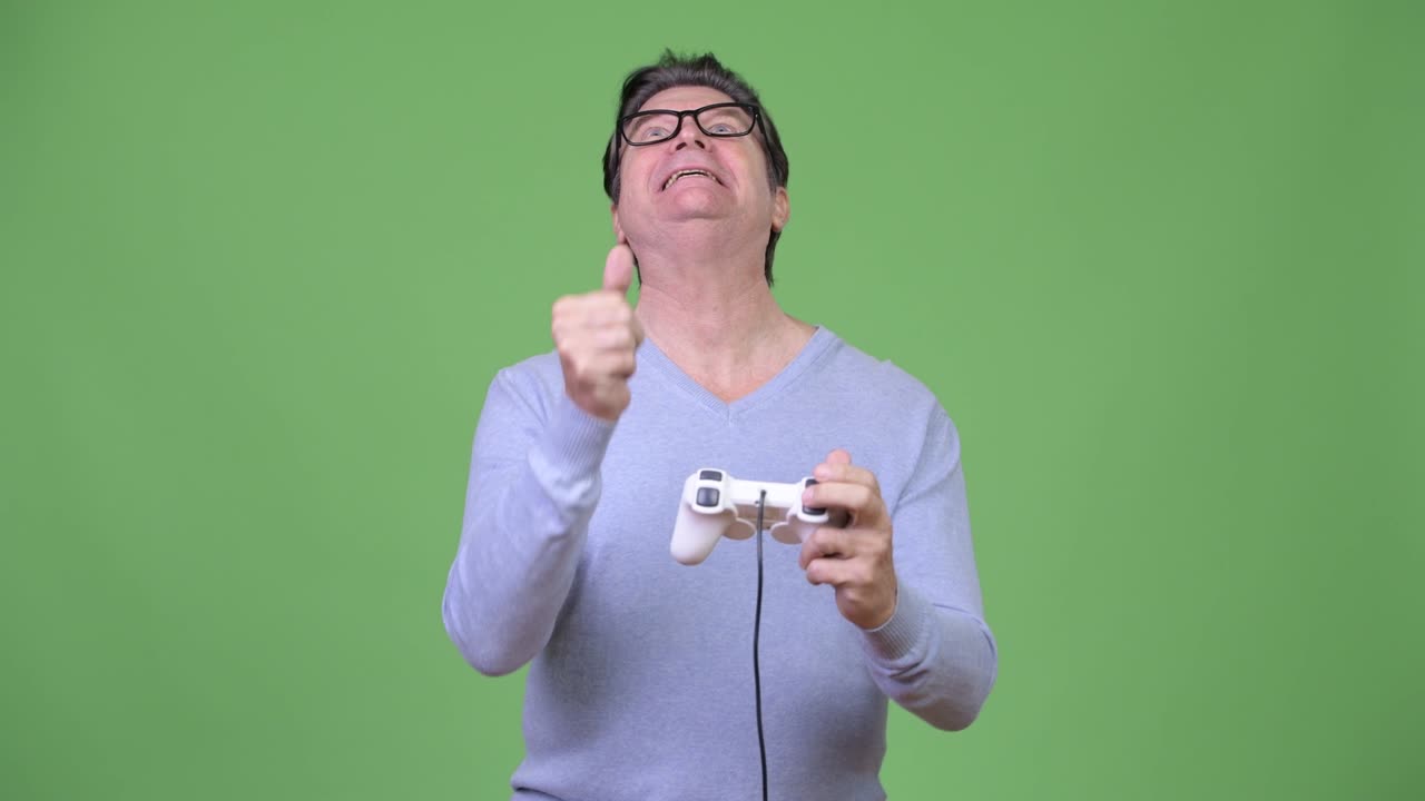 Senior handsome man playing games and losing