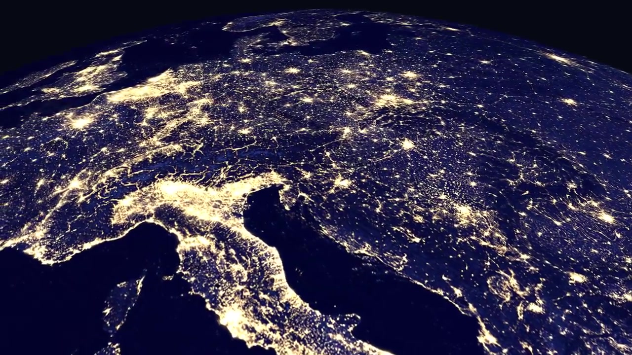 Un'animazione digitale zooma dallo spazio esterno sulle luci illuminate di una città europea di notte con didascalia