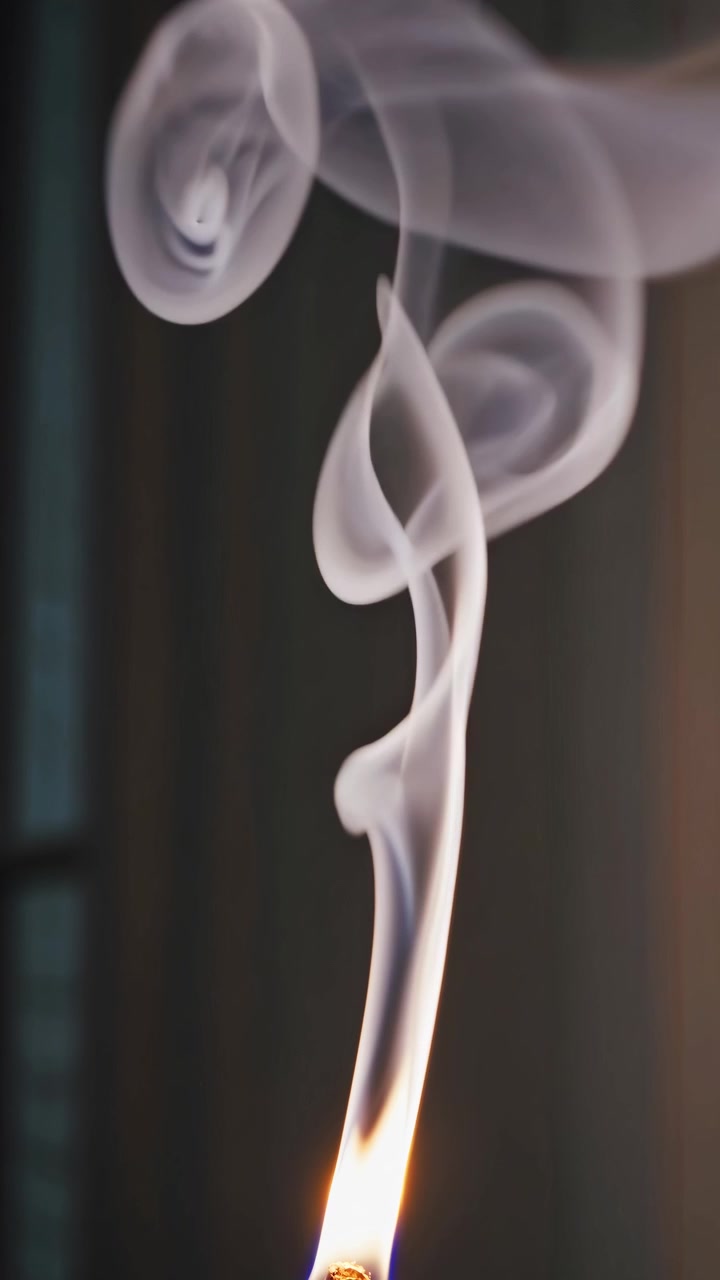Close-up of Incense Stick Burning with White Smoke Swirling