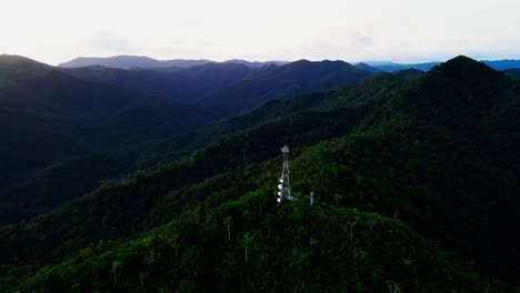 panoramic aerial orbit of lone telecommunications tower atop lush tropical mountain summit with rolling hills background - catanduanes, philippines