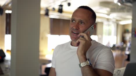 adult male businessman in a white shirt communicates on the phone and discusses important things