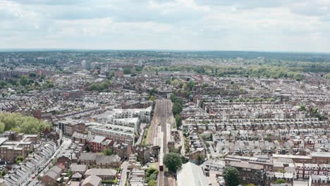 Absteigende-Drohnenaufnahme-Des-Zuges-Der-District-Line,-Der-Am-Bahnhof-Parsons-Green-In-London-Ankommt