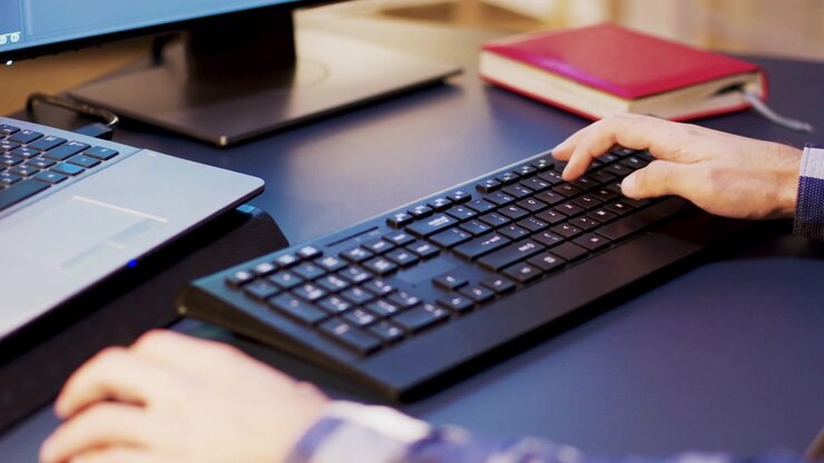 Person Typing on Computer Keyboard at Office Desk