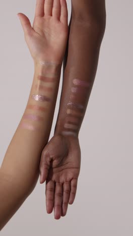 rotating close up of two women's arms with colorful swatches of different make up products