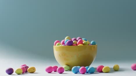 bowl with colorful easter eggs on green background with copy space