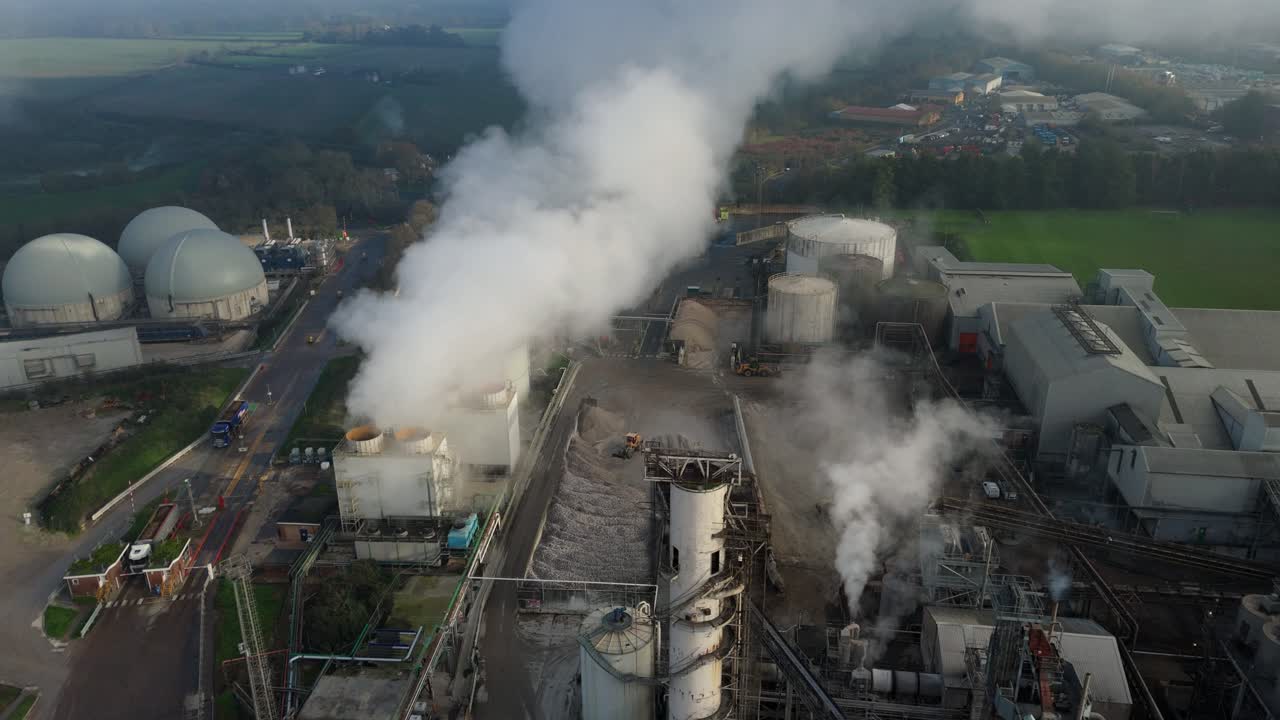 Overhead view of large scale industrial sugar factory in Bury St Edmunds UK with thick smoke from chimneys and plant vehicles moving in yards