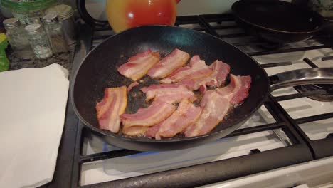 thick cut bacon sizzling in a hot skillet on a gas stove in grandma's kitchen