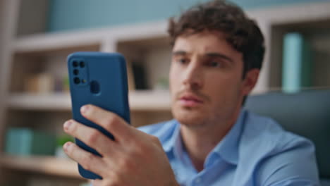 displeased guy reading message at workspace. closeup hand checking smartphone
